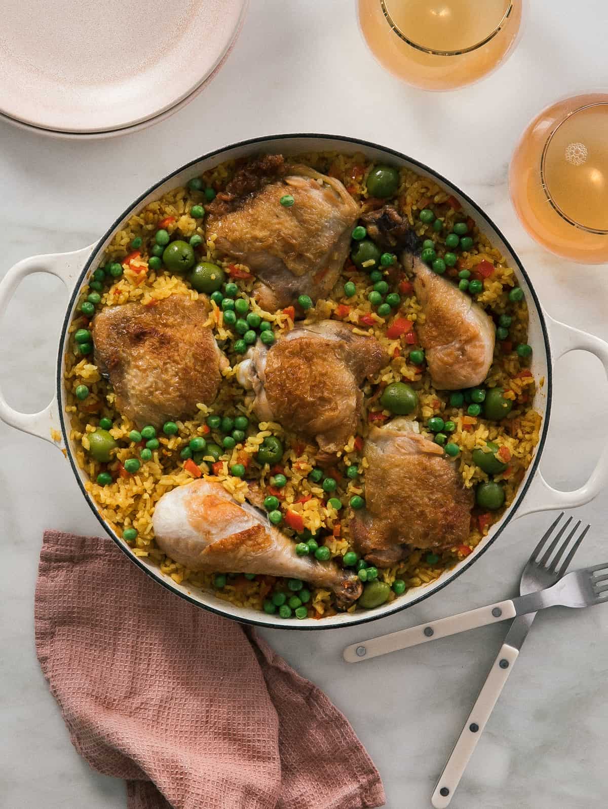 round pot of arroz con pollo with wine and forks 