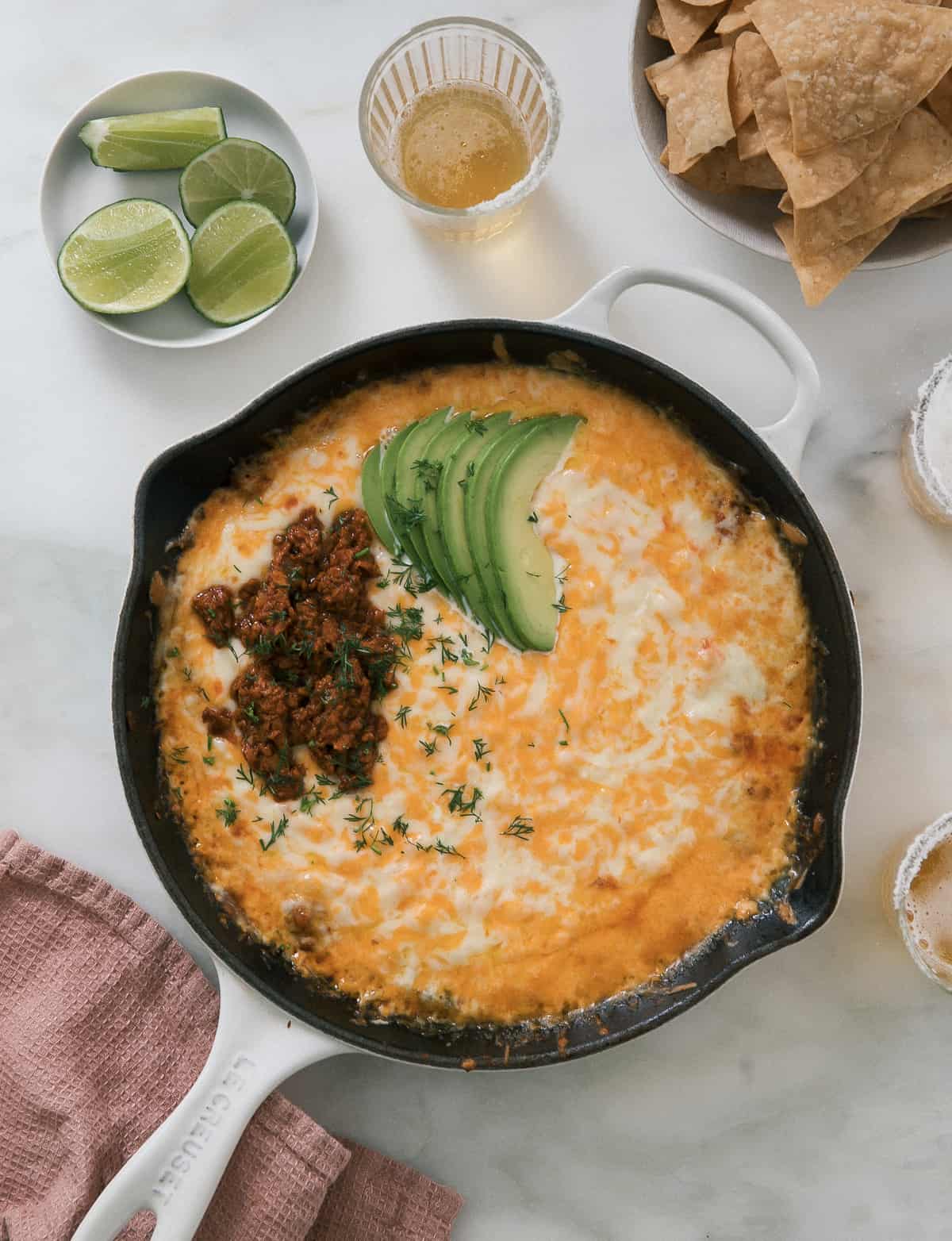 Skillet of queso fundido topped with chorizo and avocado.