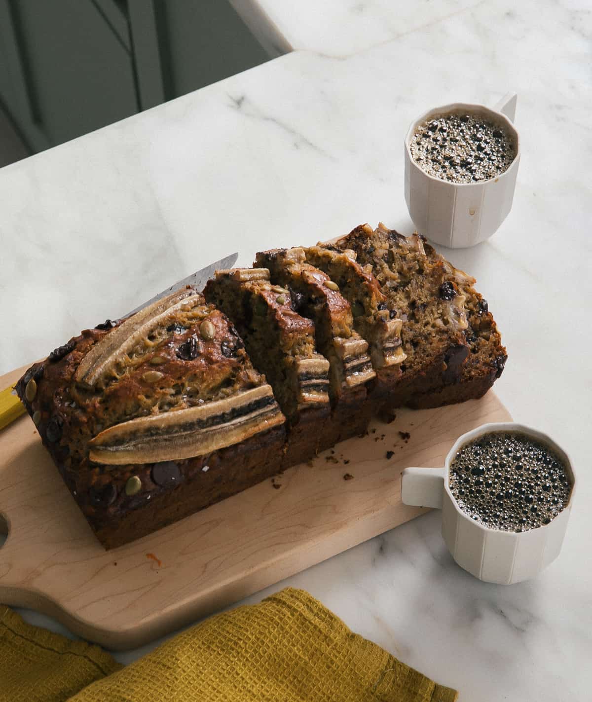 Easy Banana Bread on cutting board with coffees. 