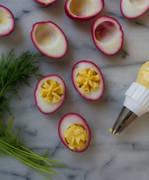 Deviled eggs being filled on counter. 