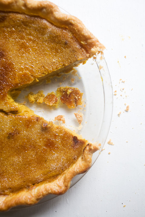 A pumpkin pie in a baking dish with slices missing.