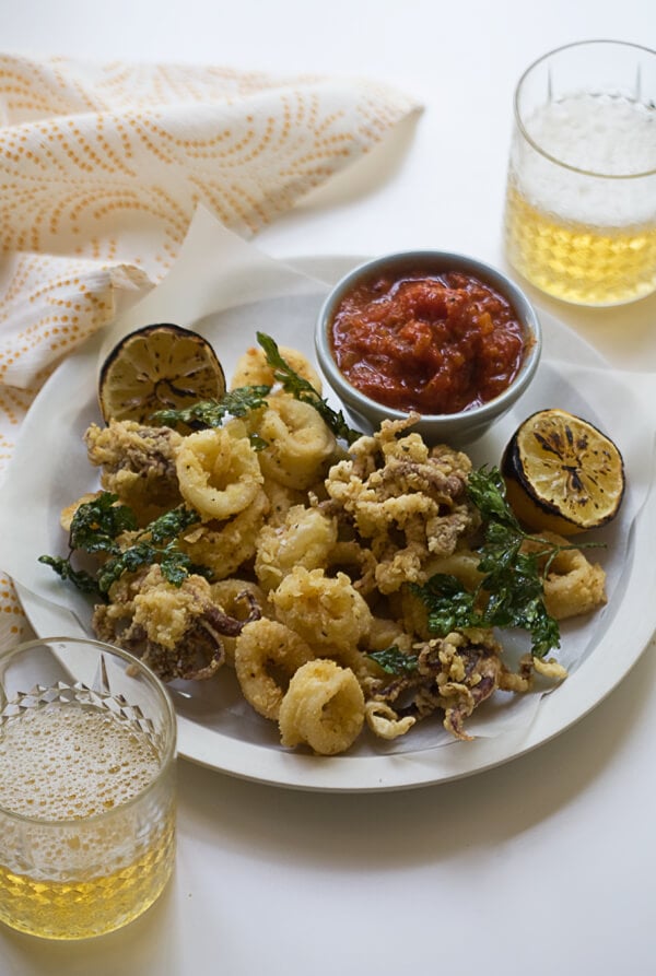 Fried Calamari on a plate with a grilled lemon and marinara sauce. 