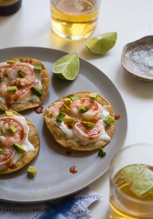 Shrimp tostadas on a plate with lime wedges.