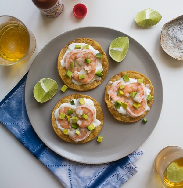 Tostadas on a plate with lime wedges and beer.