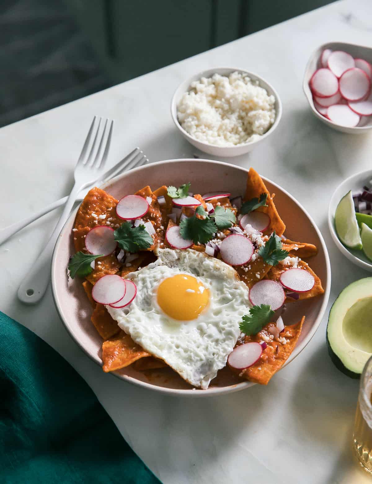 Round plate of Chilaquiles surrounded radishes, limes and avocado