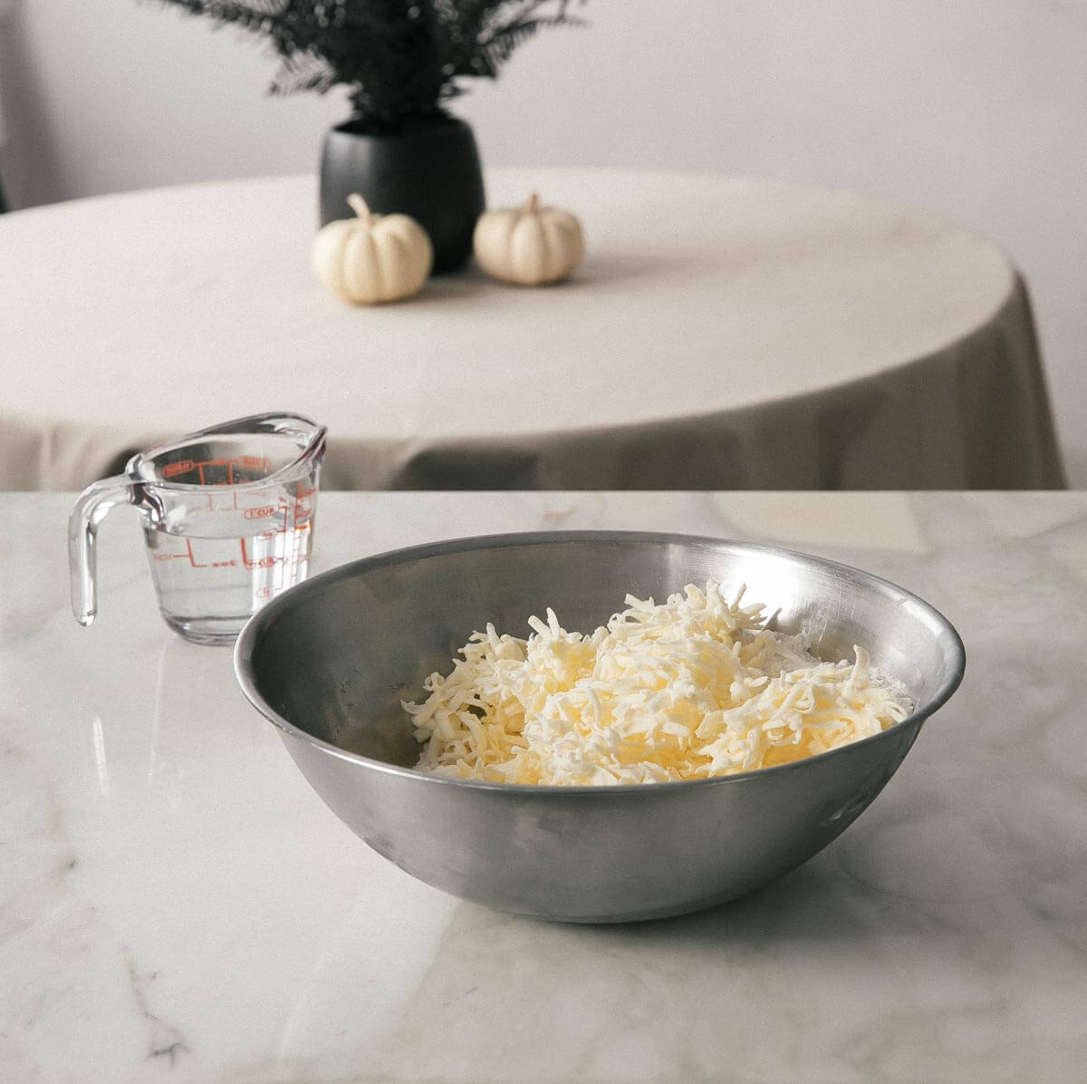 Bowl of shredded butter and flour with water on the side. 