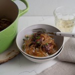 Close up image of braised chicken in a bowl with a fork.