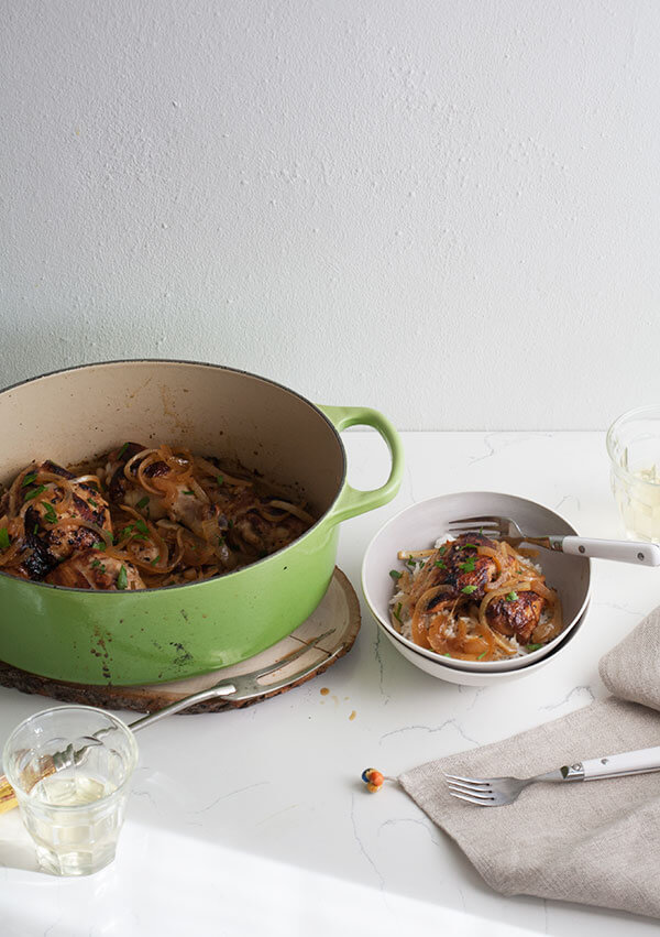 3/4 view of Pollo Frito a la Criolla in a bowl and pot with stewed onions and rice. 