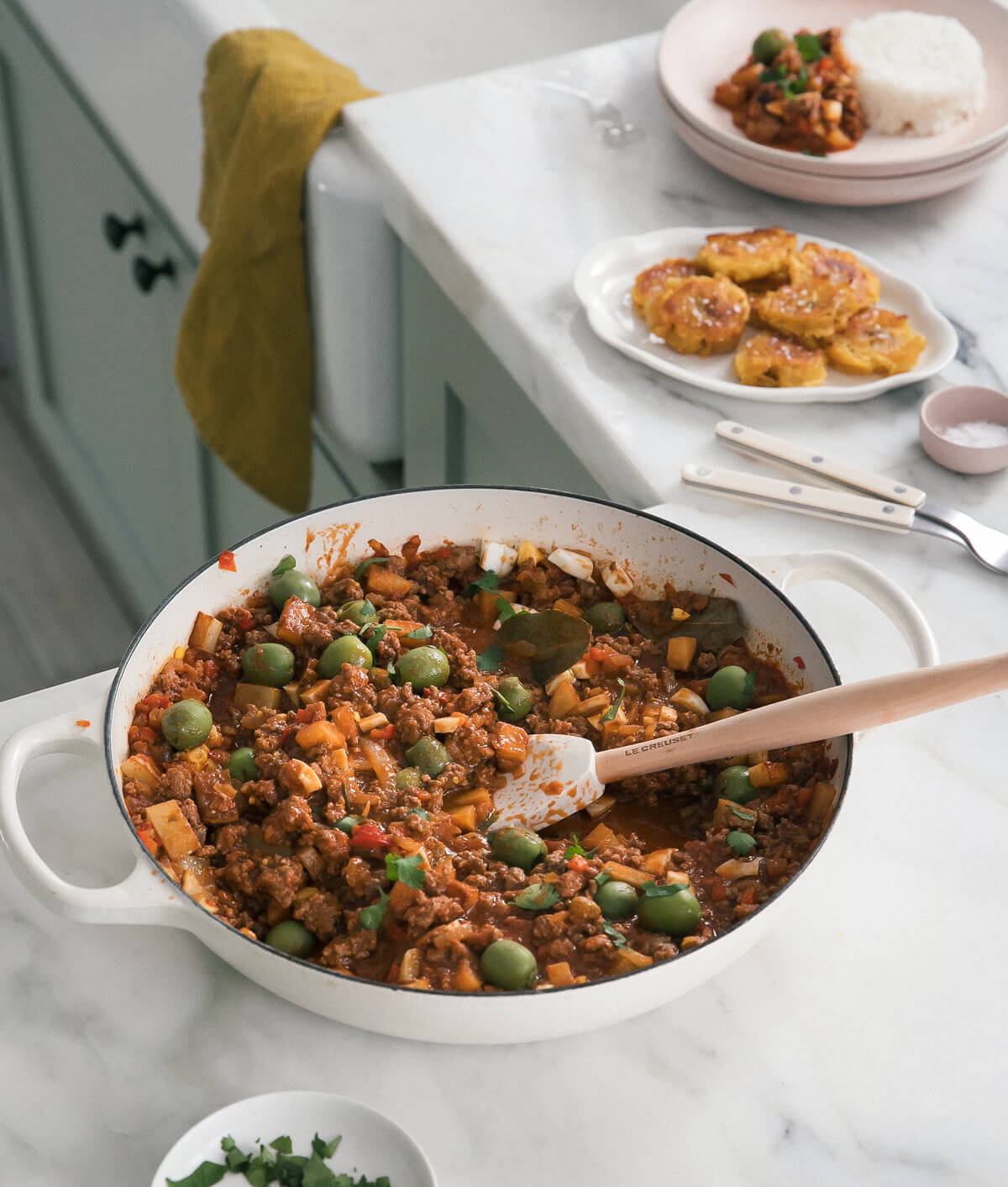 Picadillo in pot with tostones in background.