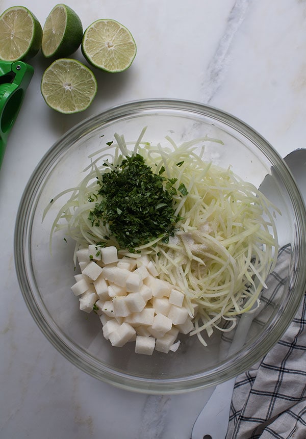 Jicama slaw being mixed in bowl. 