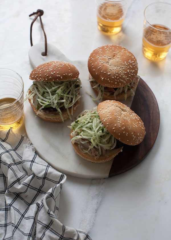 Jerk Chicken Sandwich with Jicama Slaw on serving board with beer. 