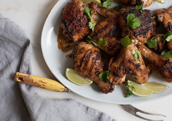 Jerk Chicken on big plate with limes and cilantro. 