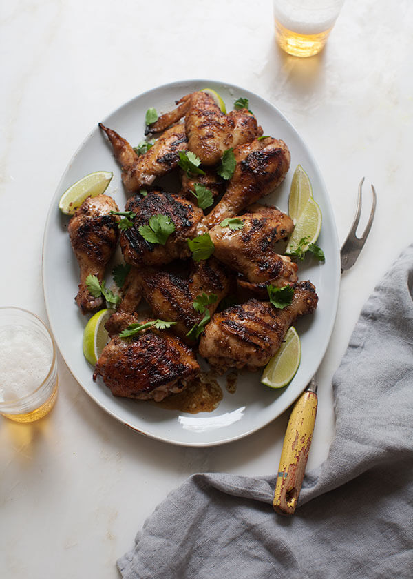 Jerk Chicken on big plate with limes and cilantro. 