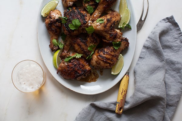 Jerk Chicken on big plate with limes and cilantro. 