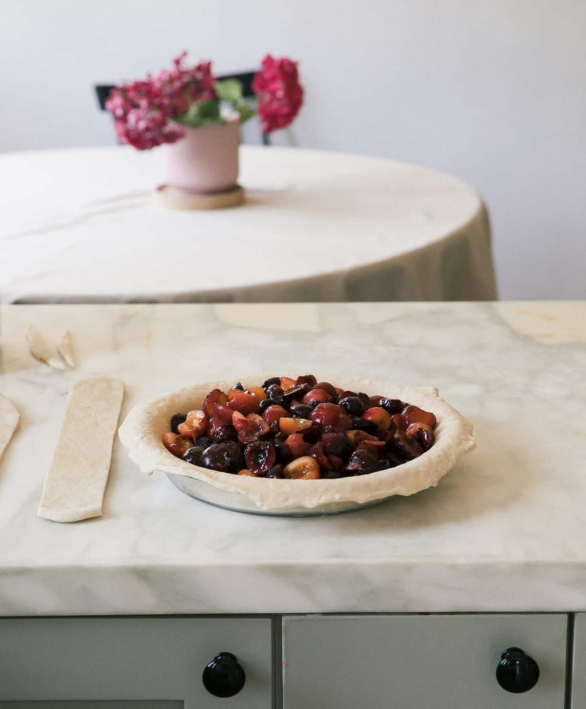 Unbaked cherry pie in a pie pan on a counter.