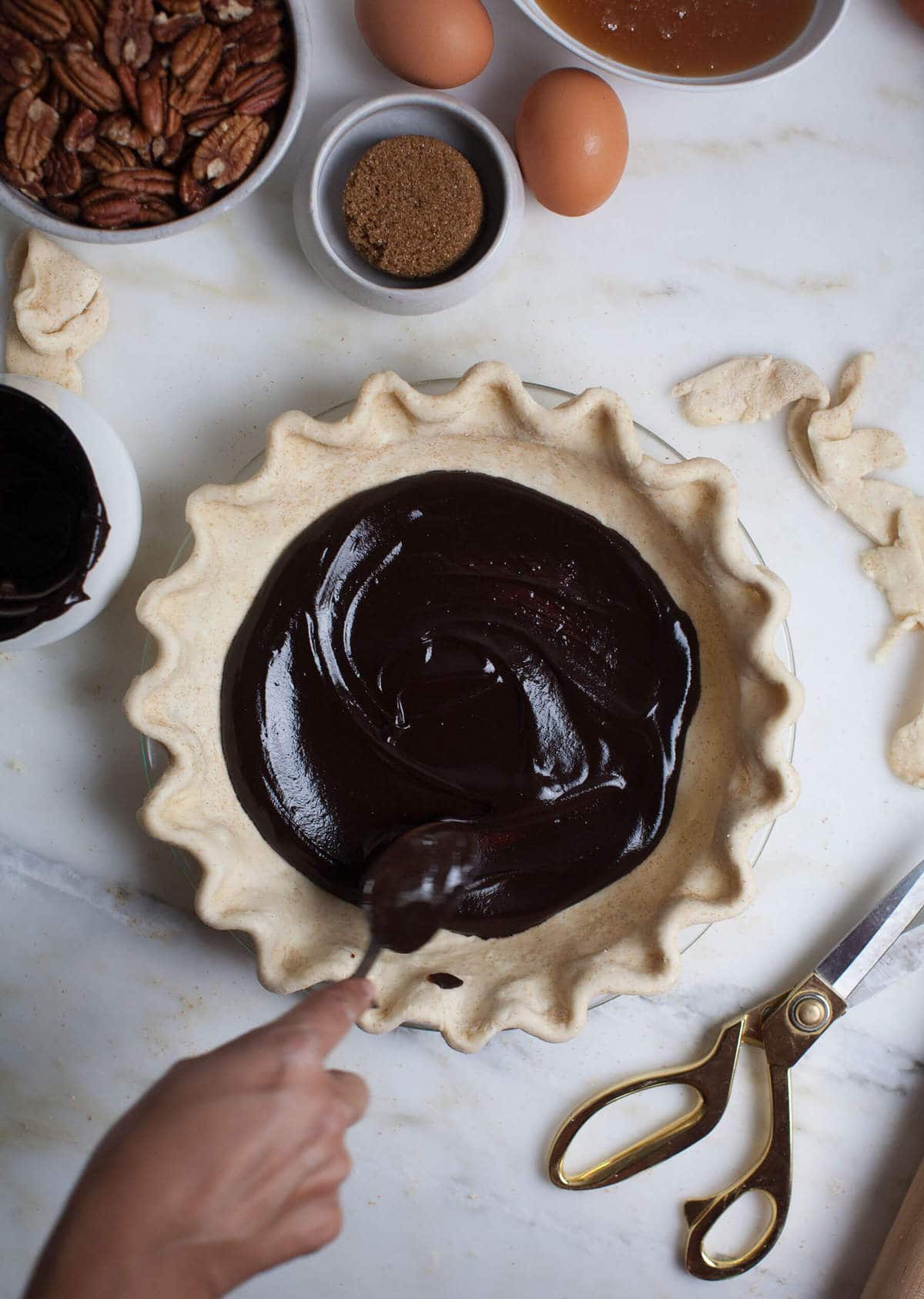 Chocolate being smeared onto pie crust. 