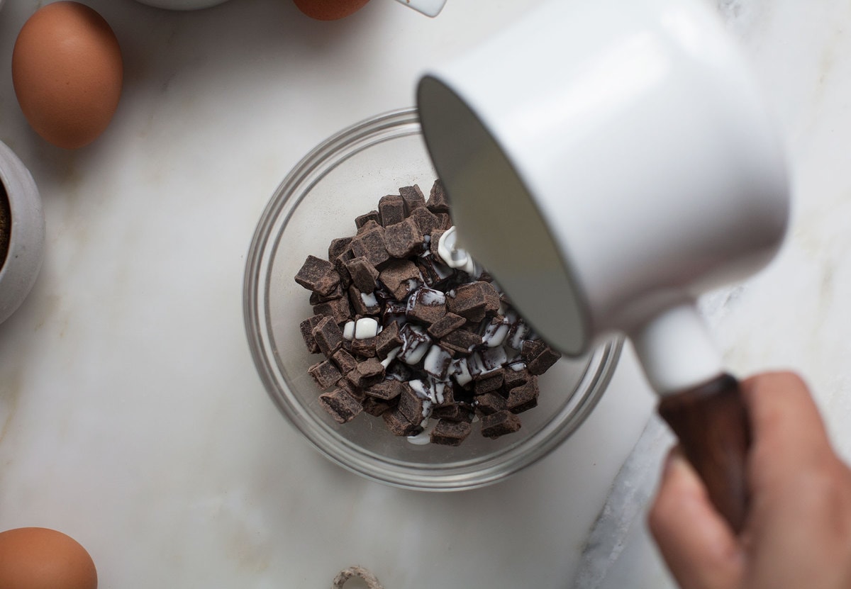 Pouring heavy cream over chopped chocolate. 