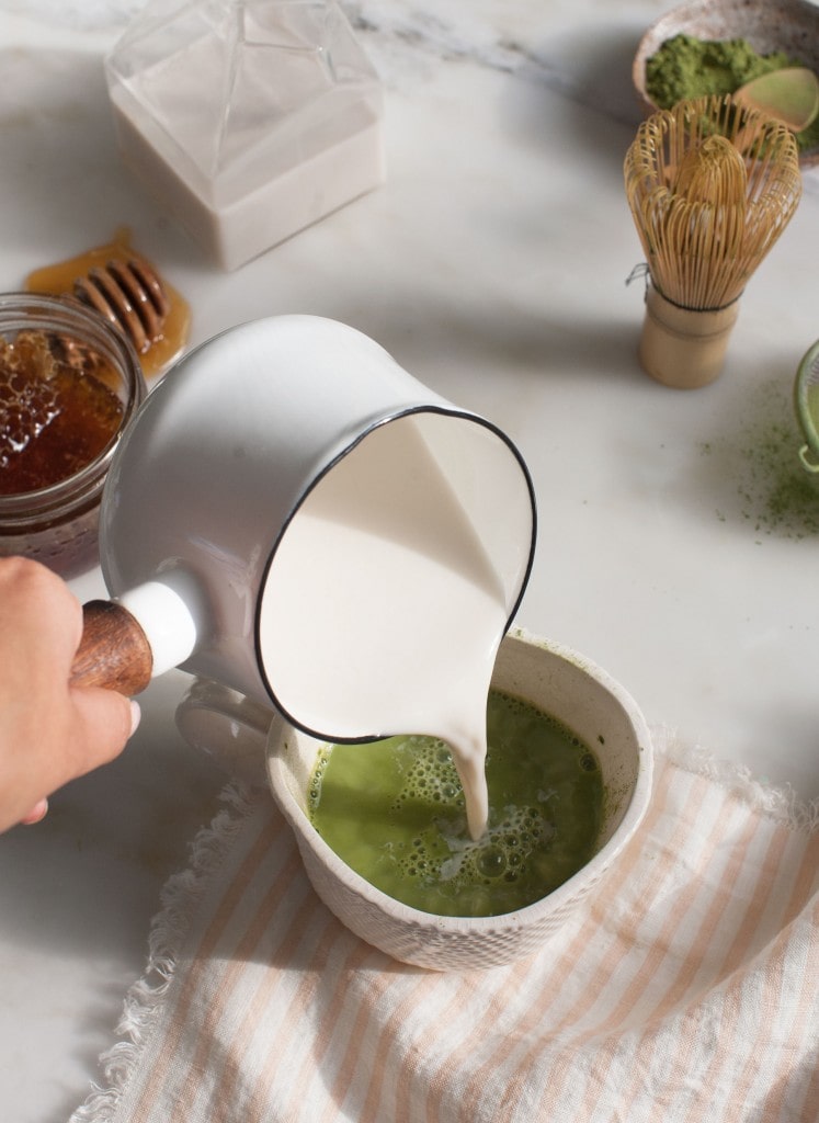 milk being poured into a cup of matcha
