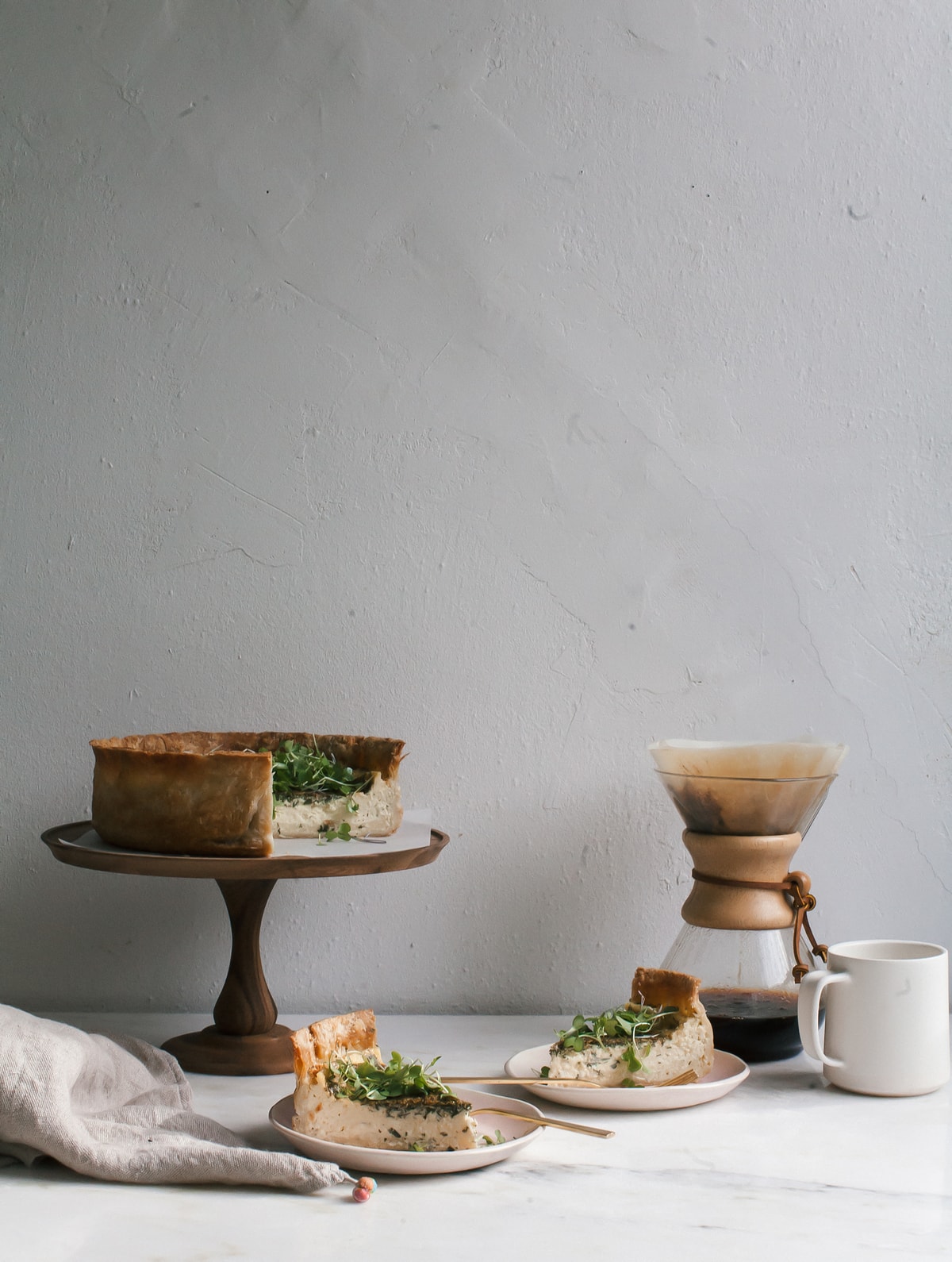 Quiche with Gruyére in slices on plates with a side of coffee. 