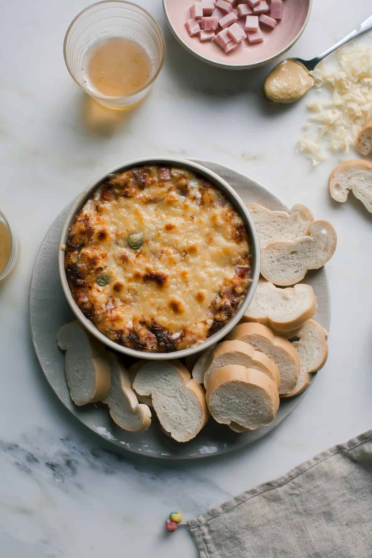 Warm Cuban Sandwich Dip on a plate with bread. 