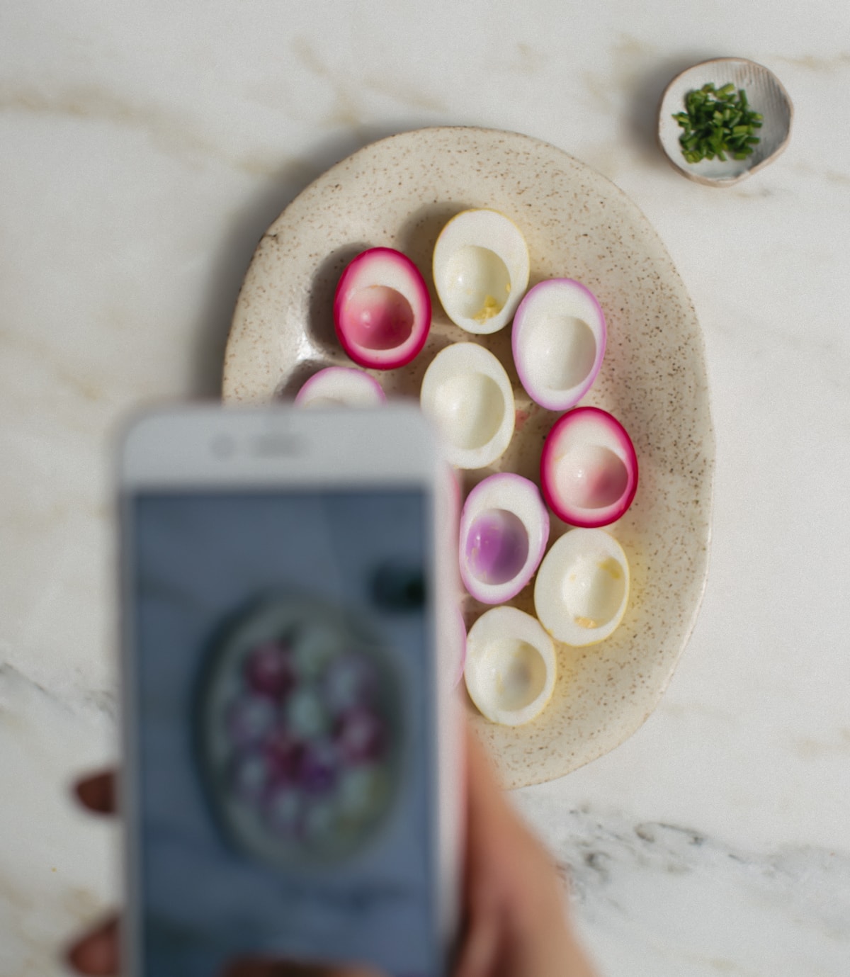 Phone taking a picture of pickled egg whites on a platter. 