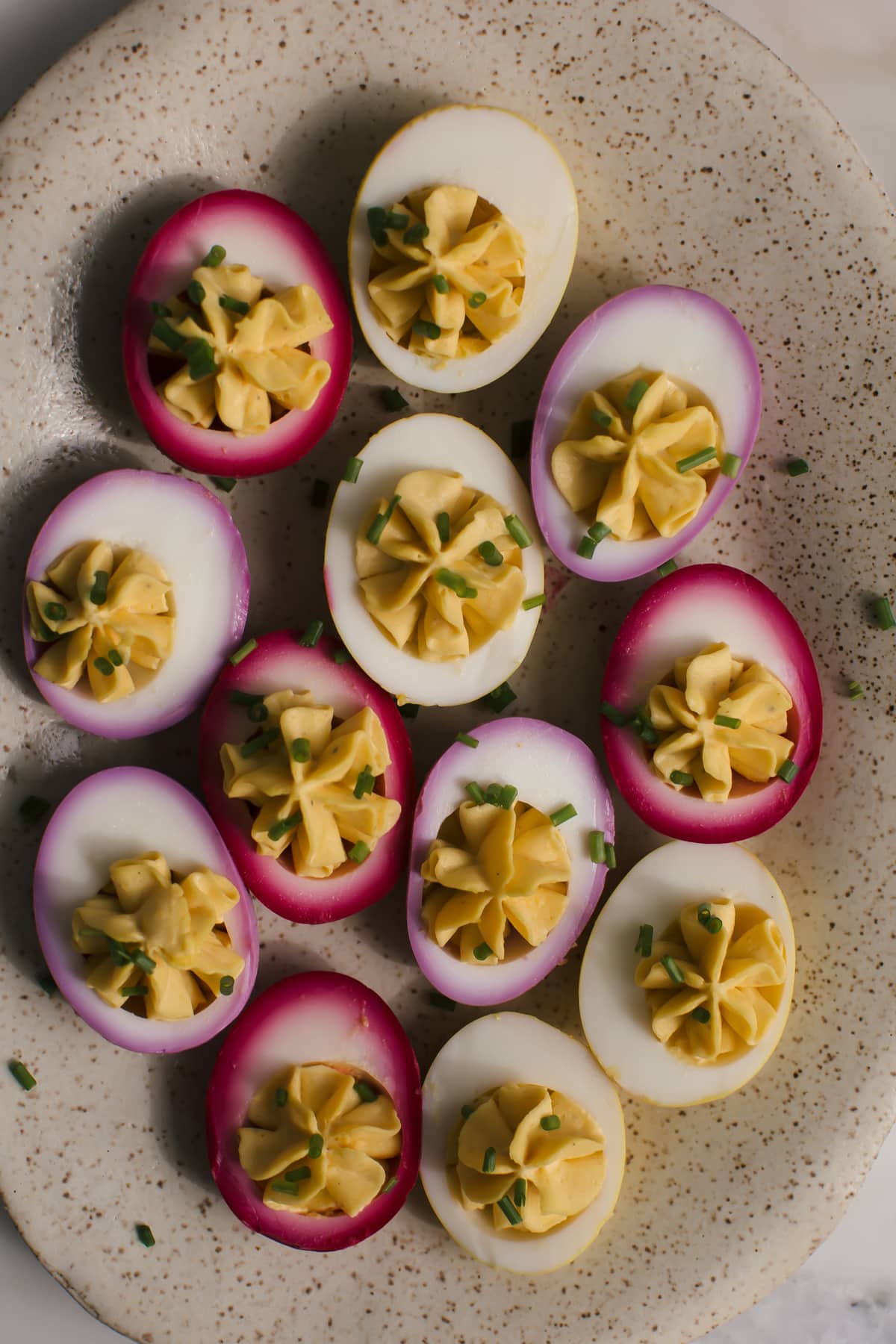 Close up image of naturally dyed pickled deviled eggs on a plate.