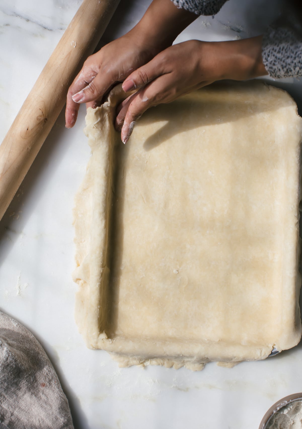 Pie crust being shaped to pie a pie pan.