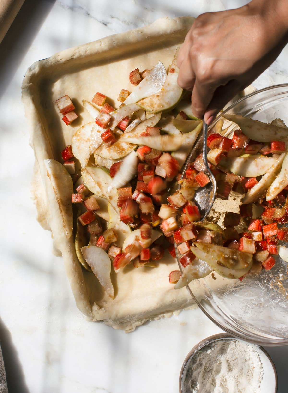 Pie filling being poured into an unbaked pie crust. 