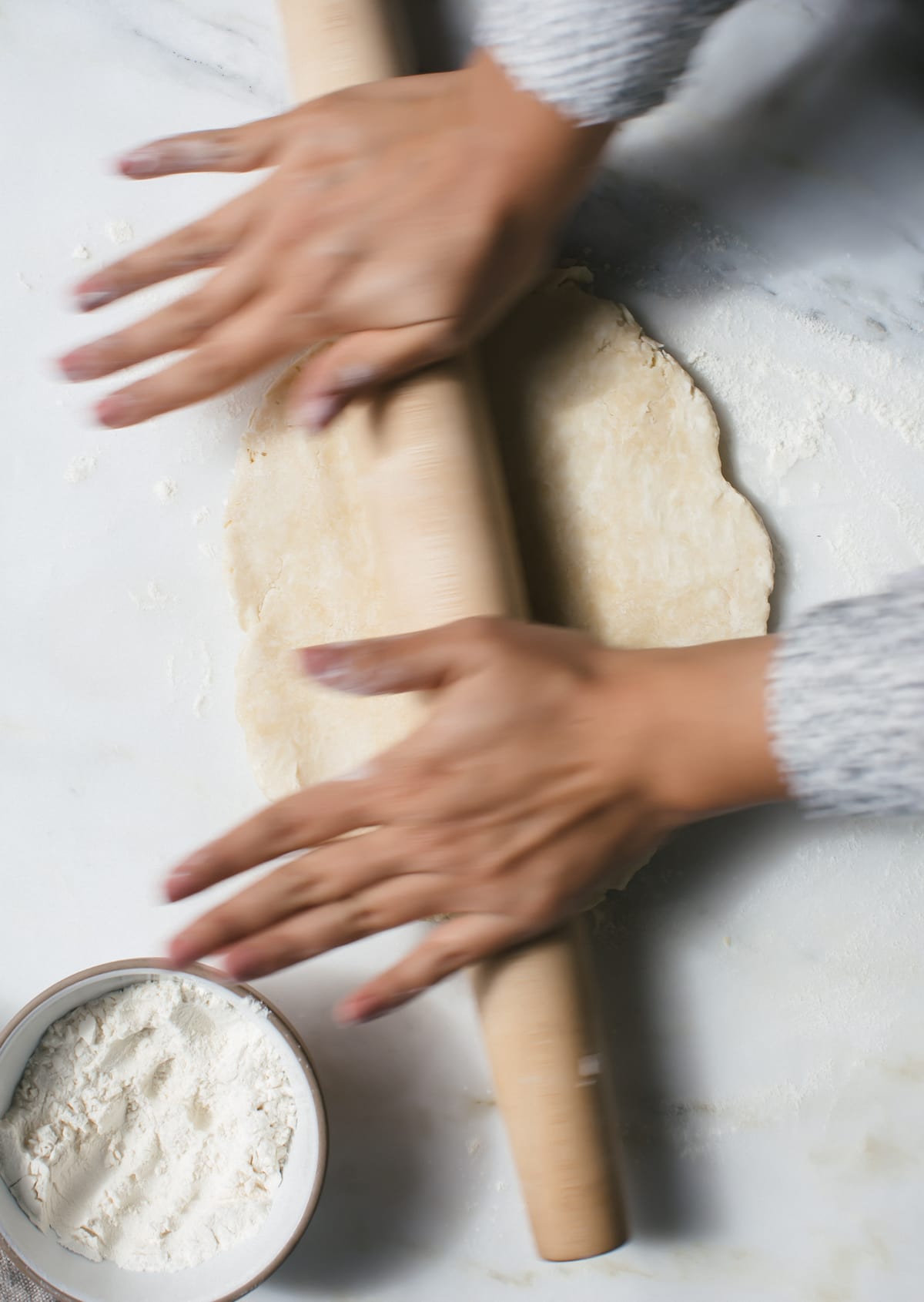 Pie crust being rolled out with a rolling pin.