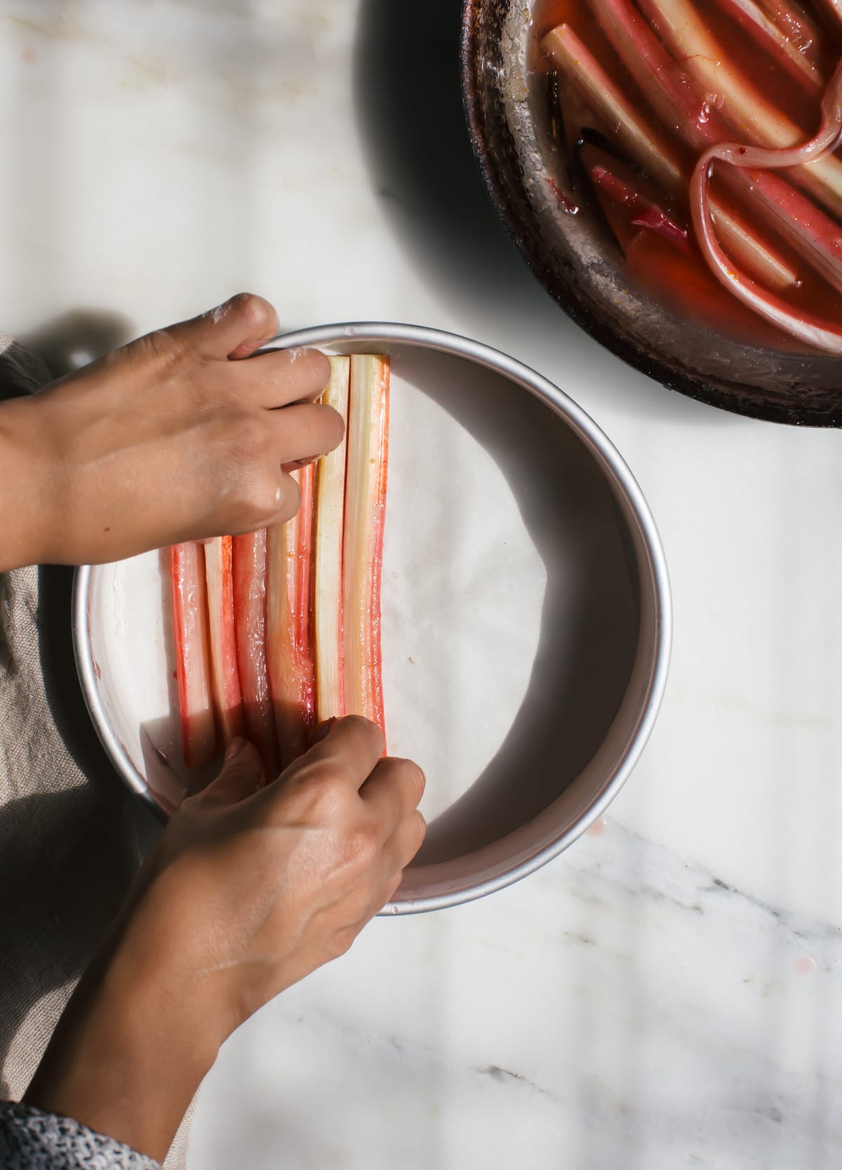 Cooked rhubarb being placed inside a cake pan.