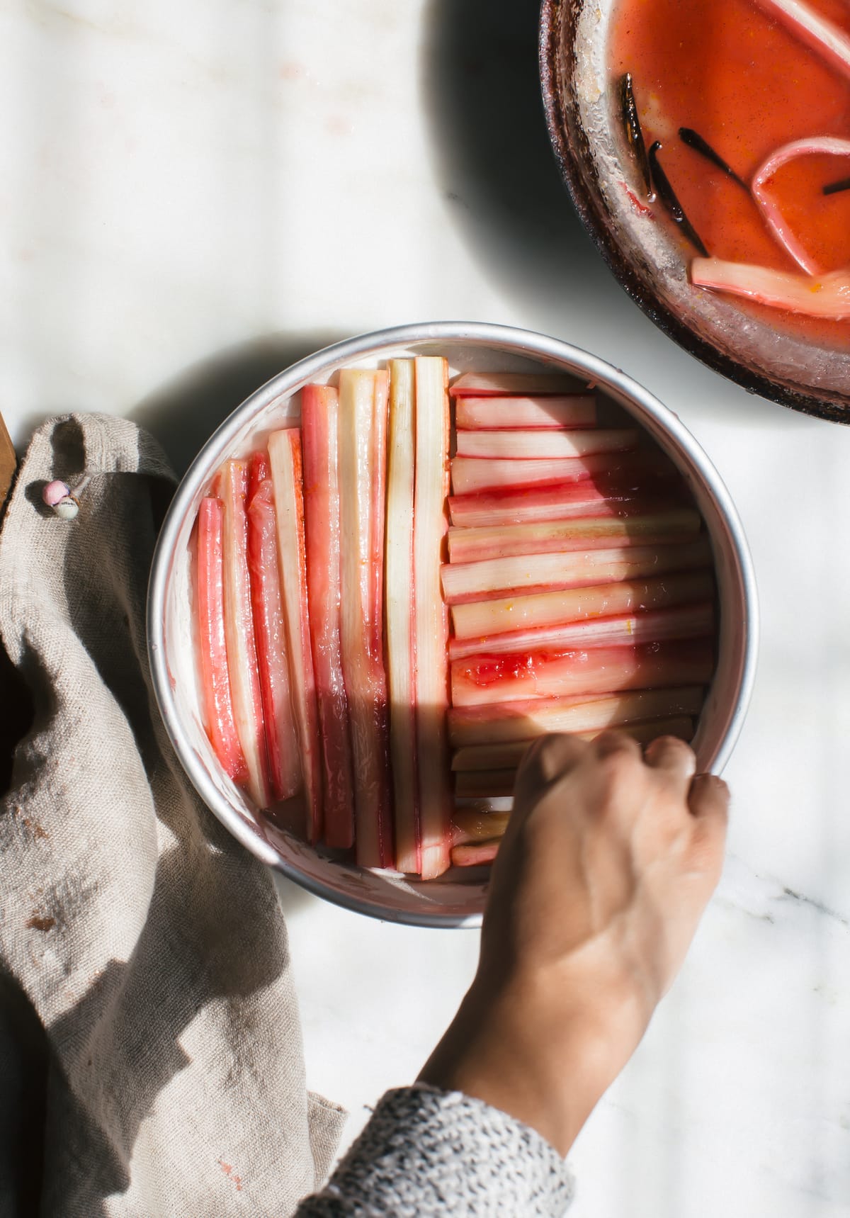 Rhubarb ribs being placed inside a cake pan.