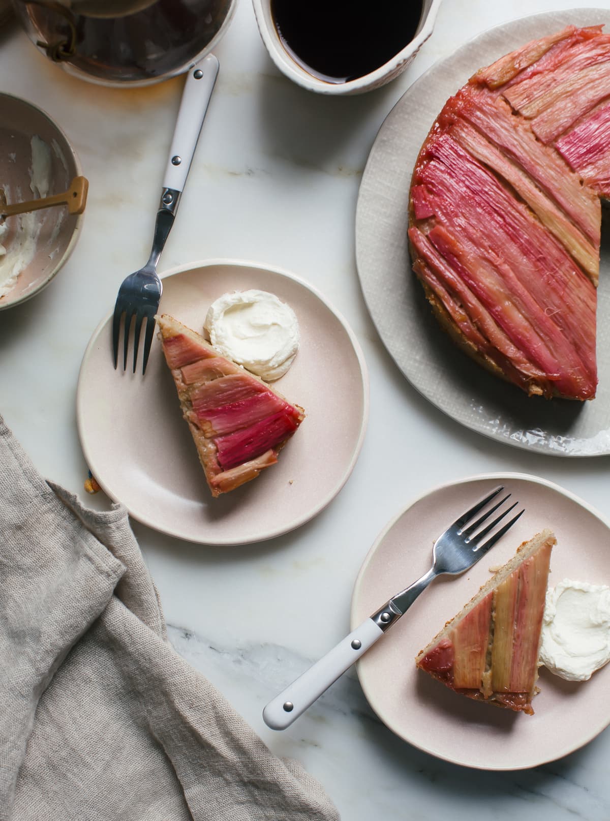 Slices of rhubarb upside down cake on a plate with whipped cream.