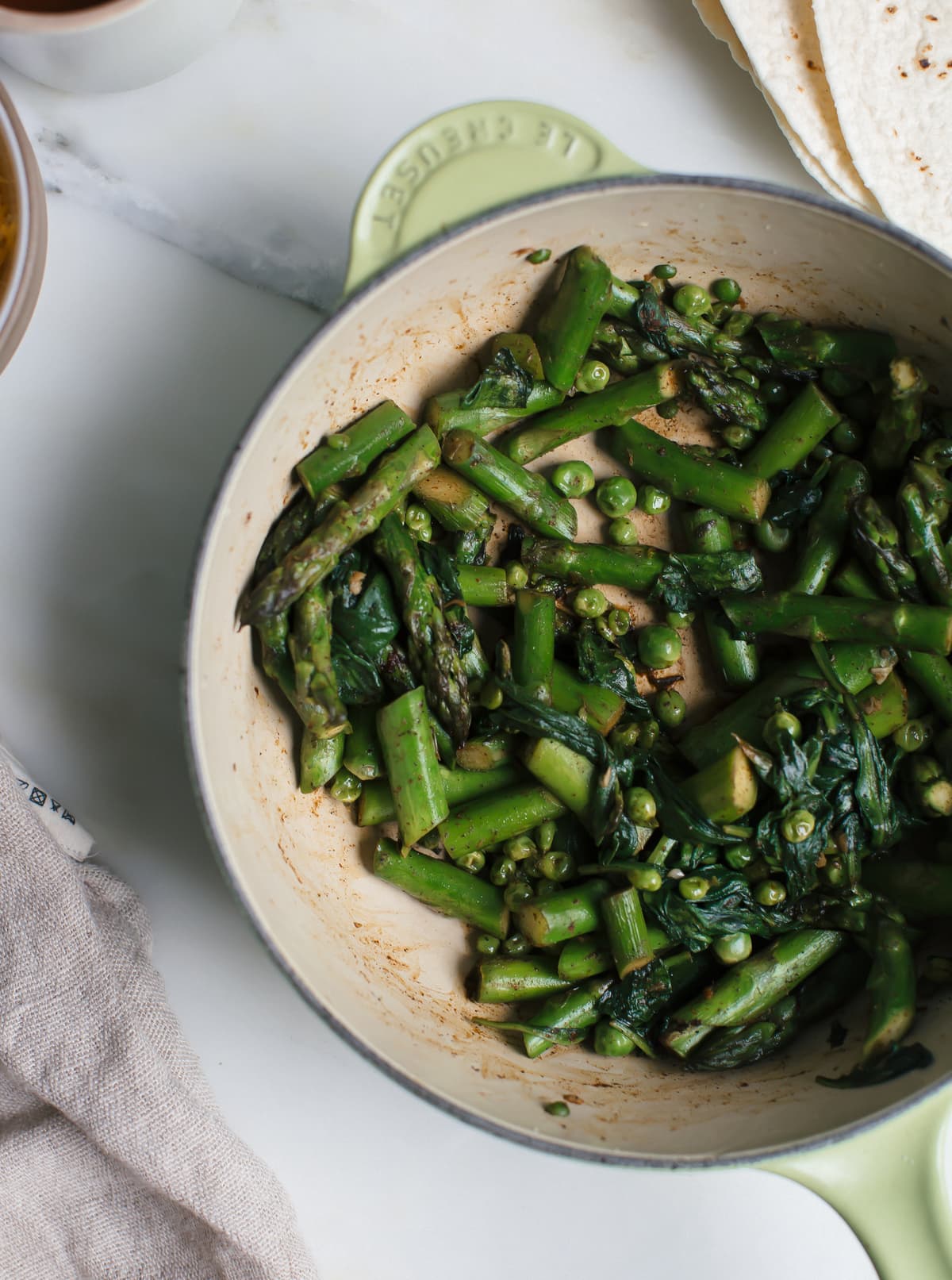 Cooked spinach and asparagus in a skillet.