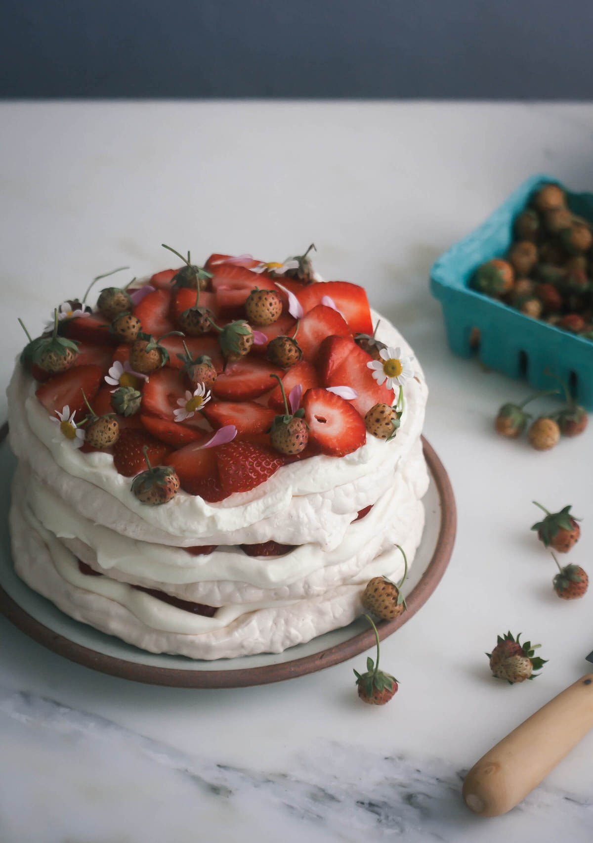 3/4 view of eton mess on a plate topped with sliced and baby strawberries. 