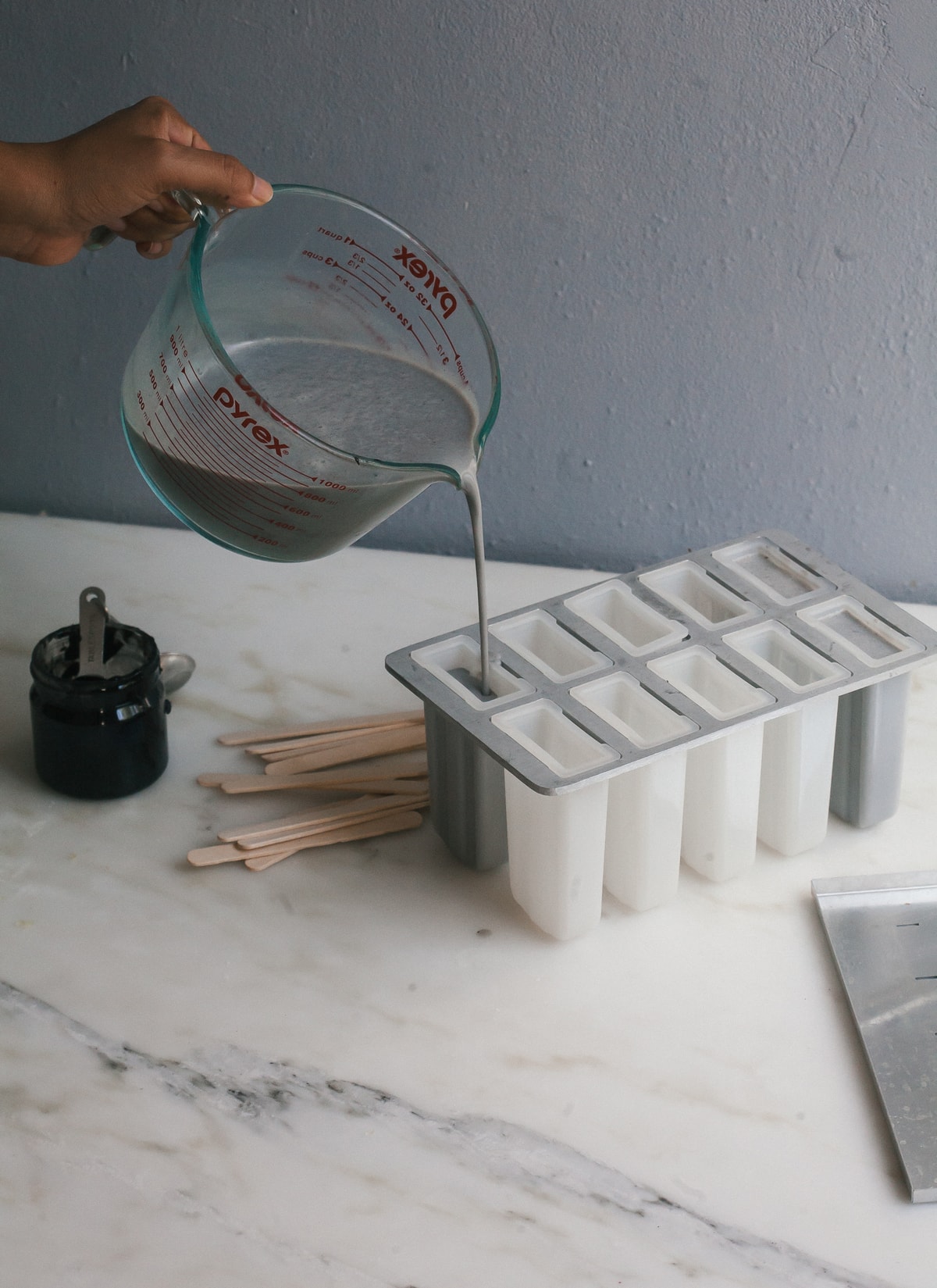 Popsicle mixture being poured into popsicle molds. 