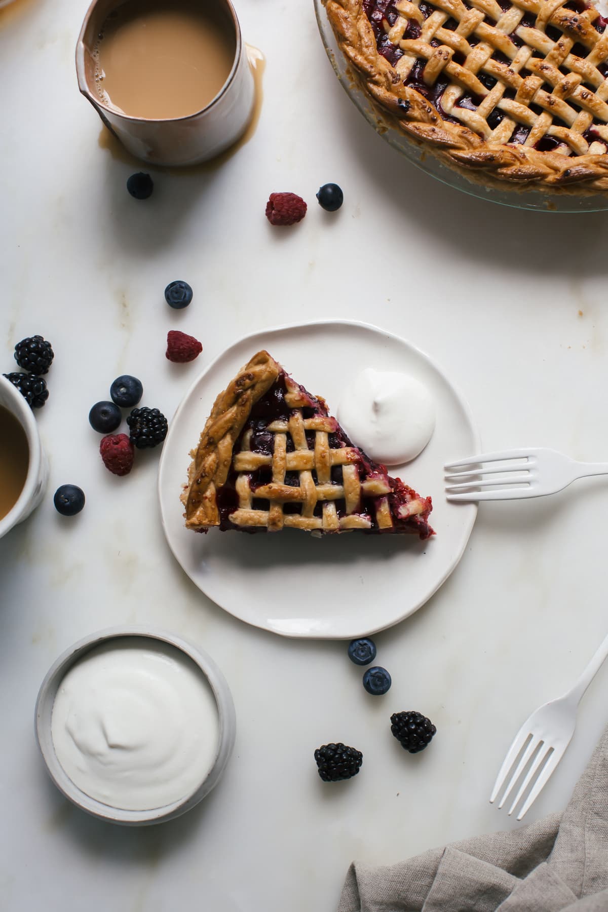 Close up image of mixed berry pie on a plate with whipped cream.