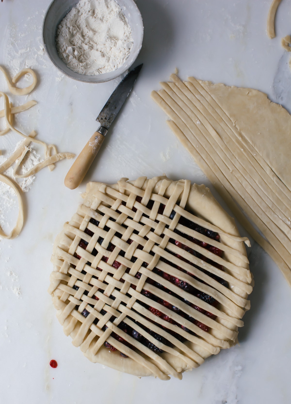 process shot of pie crust being layered on a berry pie. 