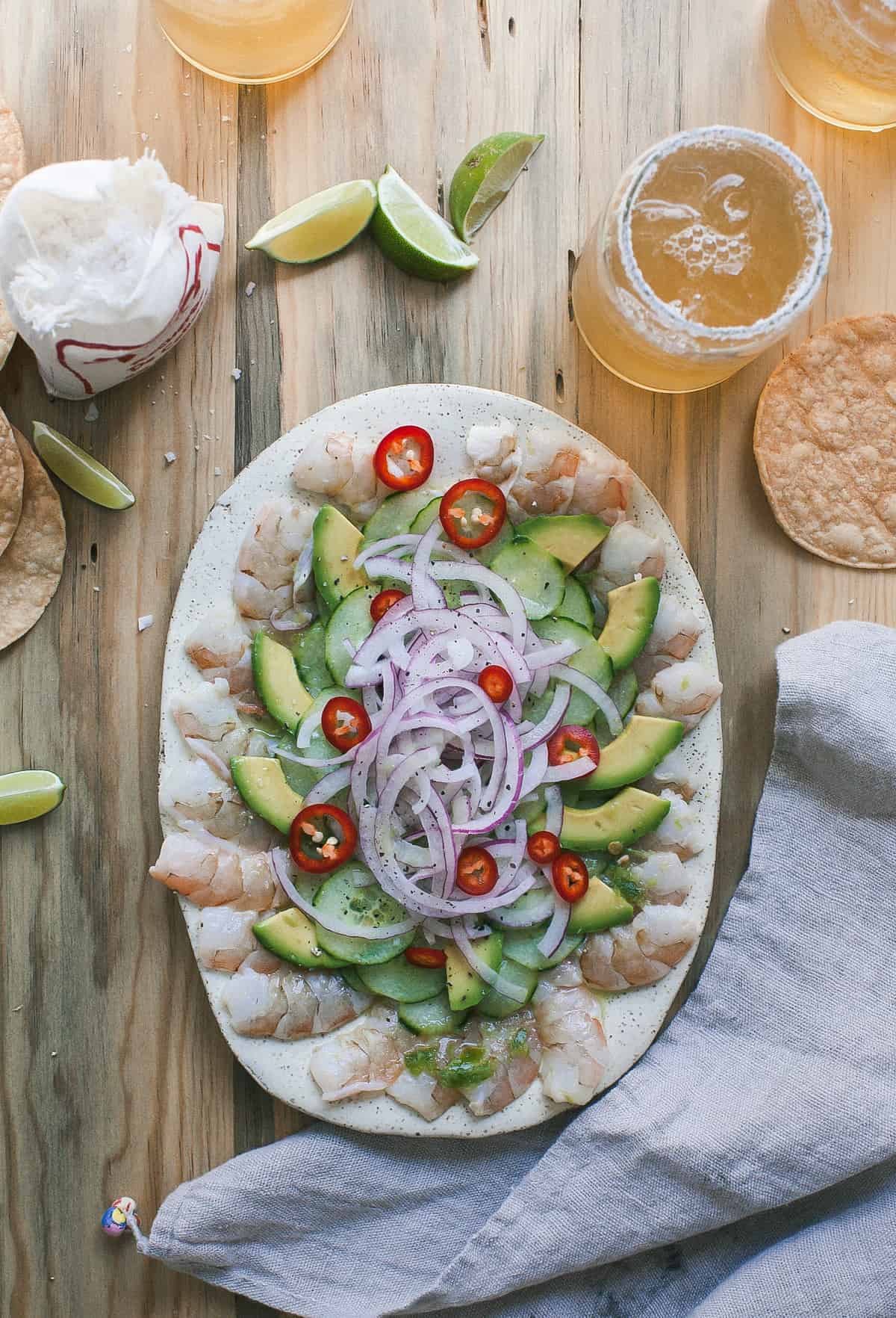 Overhead image of aguachile on a platter with sliced vegetables.