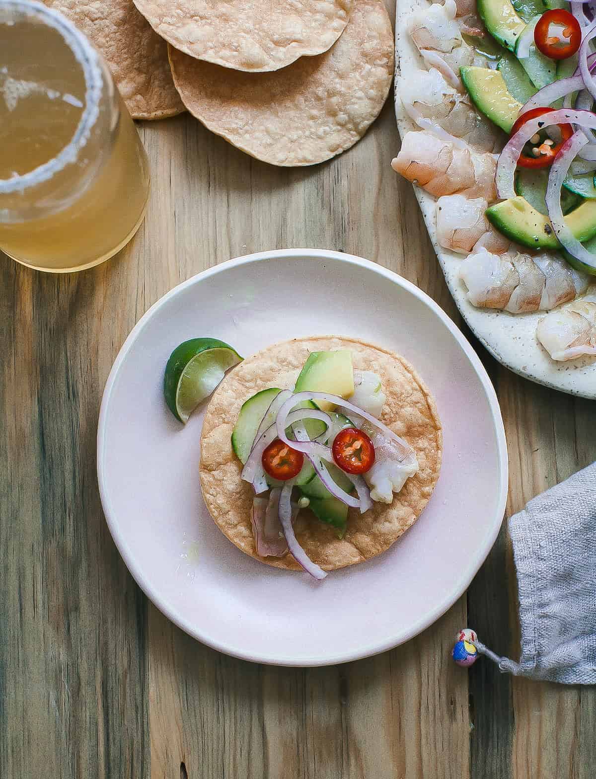 Aguachile served on a tostada with a lime wedge.