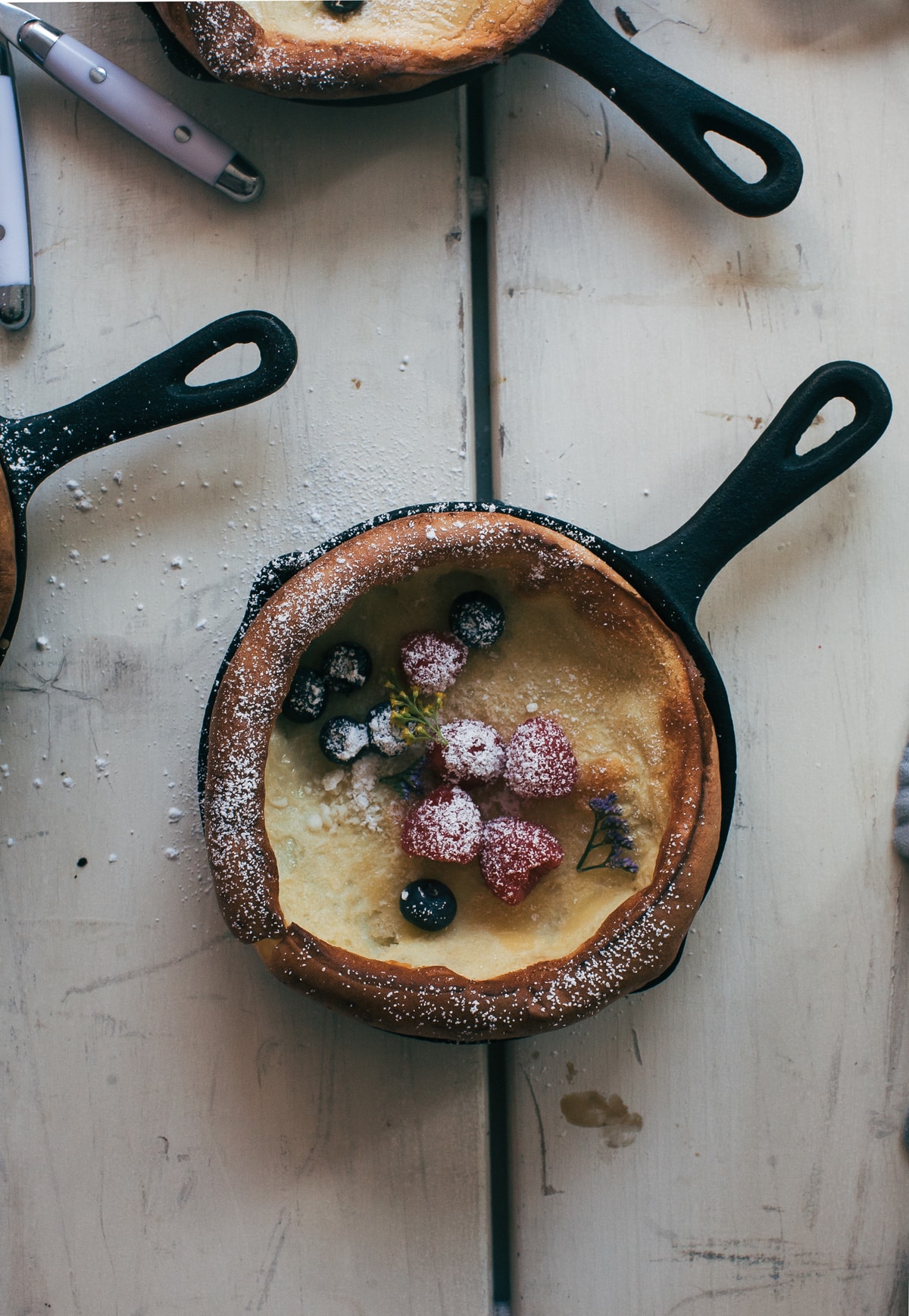 Dutch baby in a skillet topped with powdered sugar.