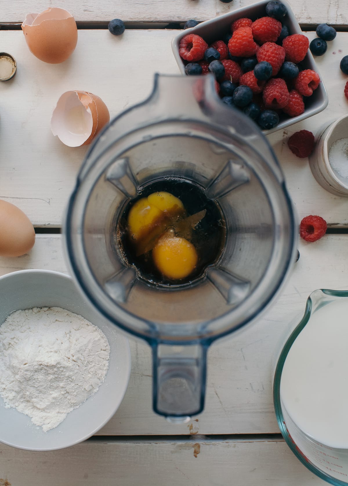 Eggs in a blender with pancake ingredients near by.