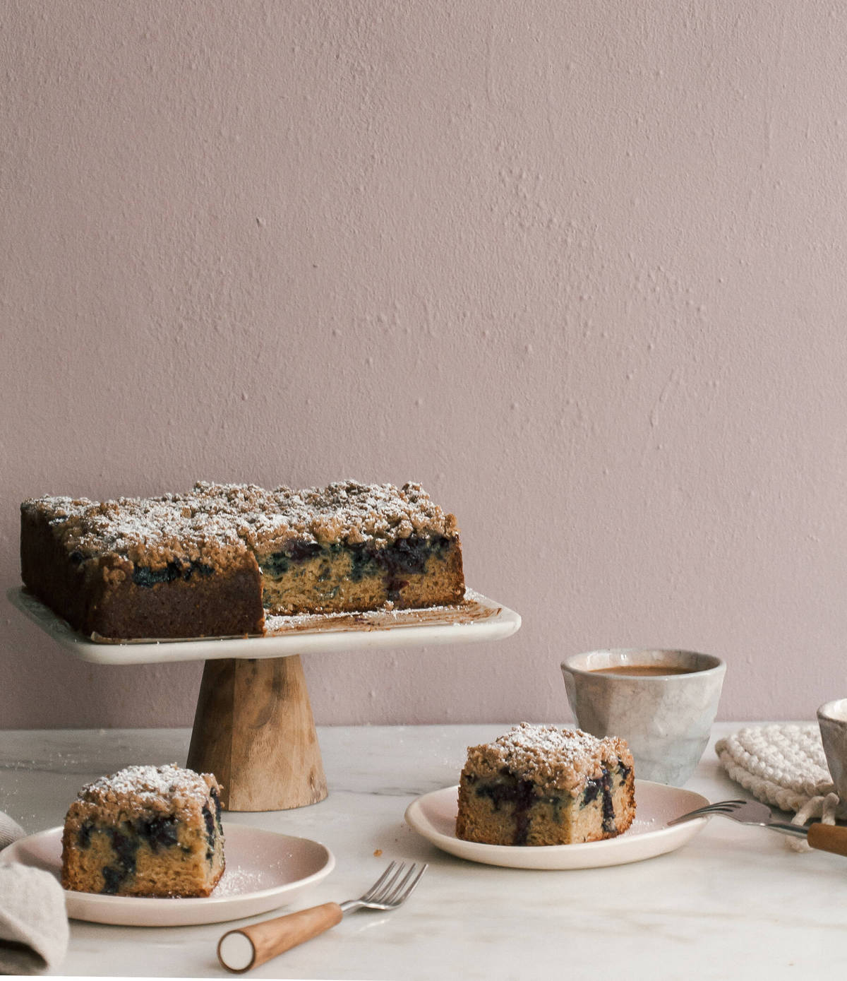 Blueberry coffee cake on a cake stand on slices on plates.