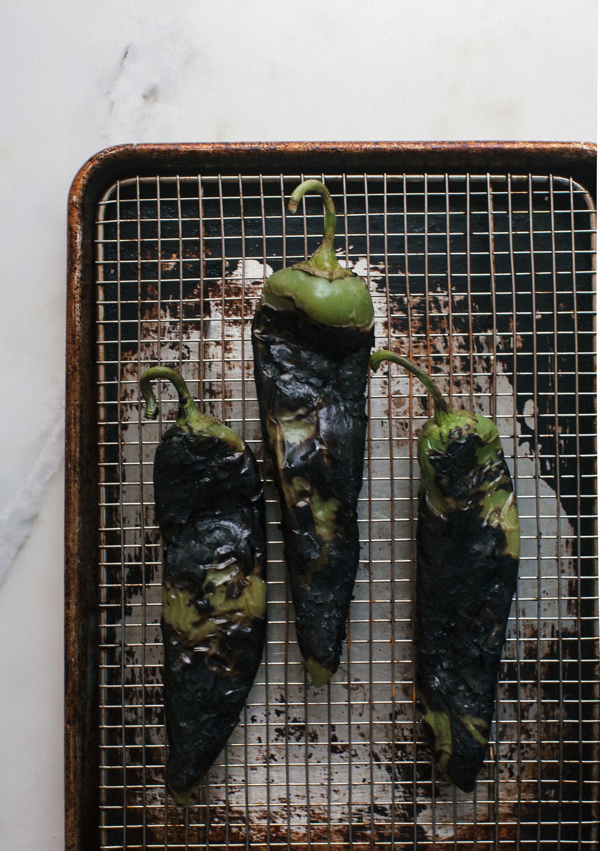 Charred hatch chiles on a wire rack.