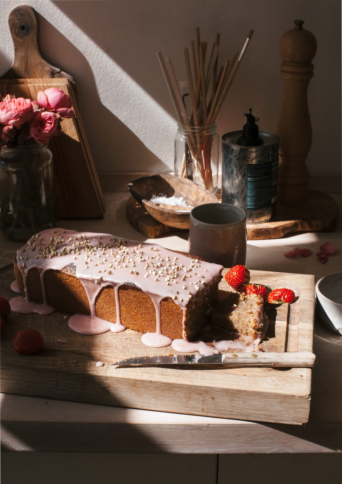 Close up image of a glazed strawberry rye loaf cake on a cutting board. 