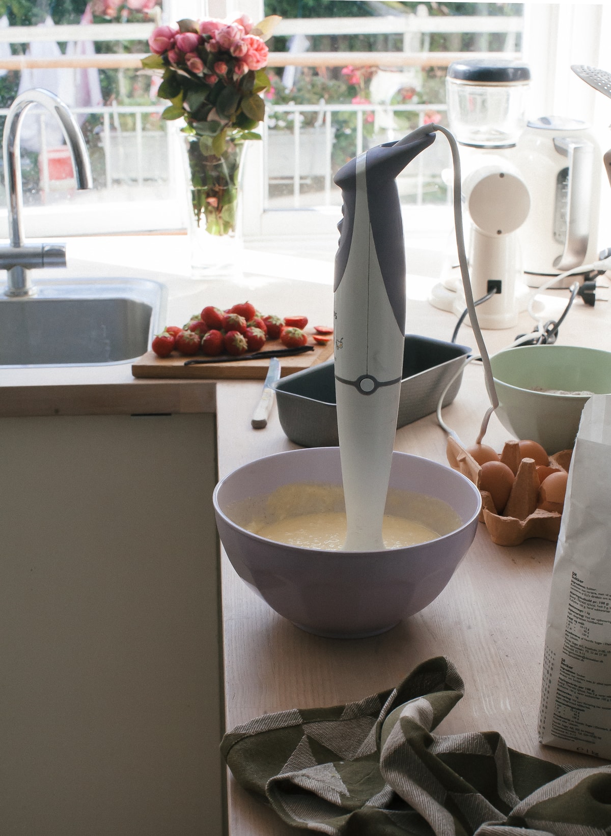 Batter being mixed with an immersion blender in a large bowl. 