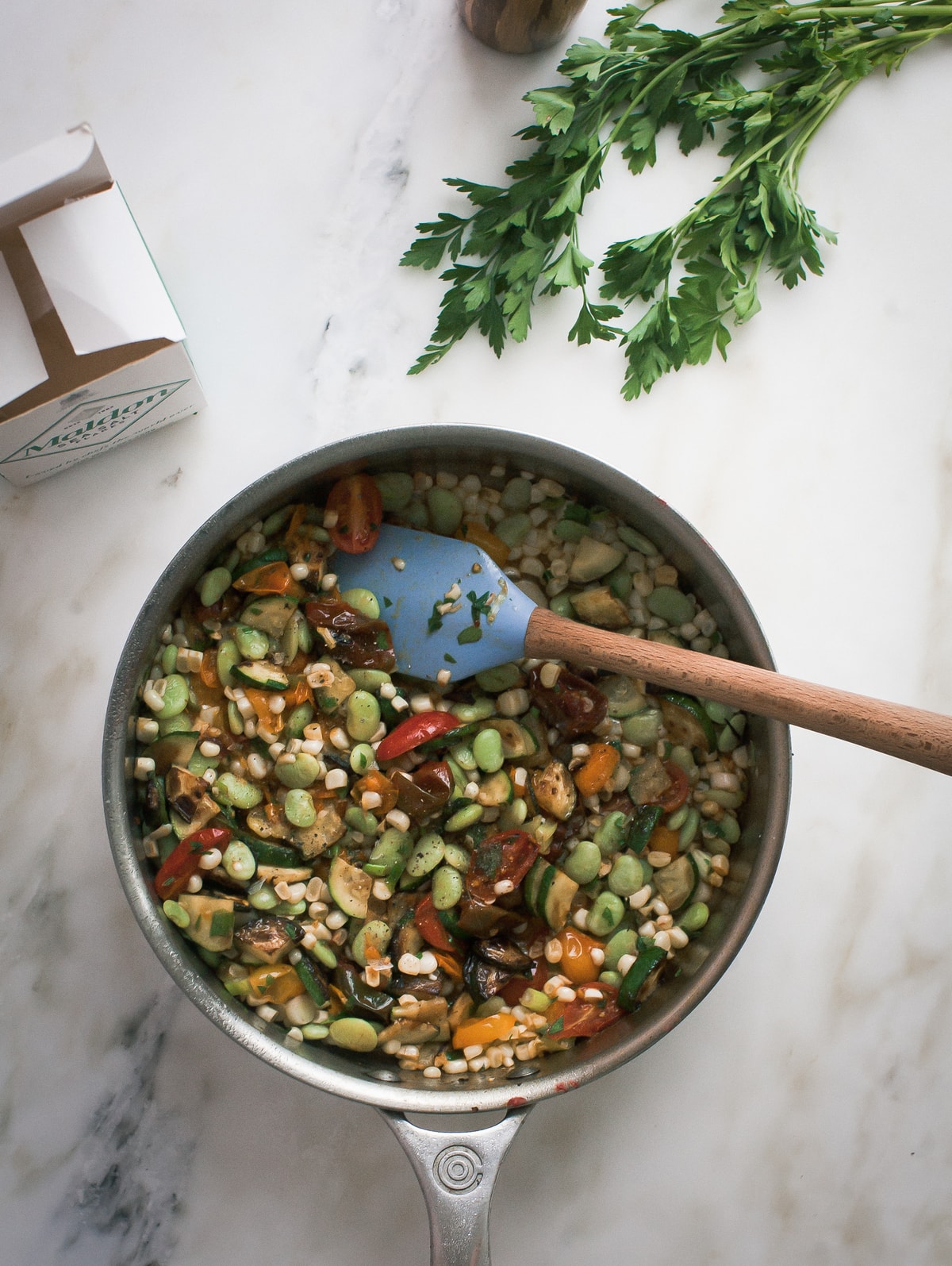 Cooked vegetables and lima beans in a skillet with a spatula.