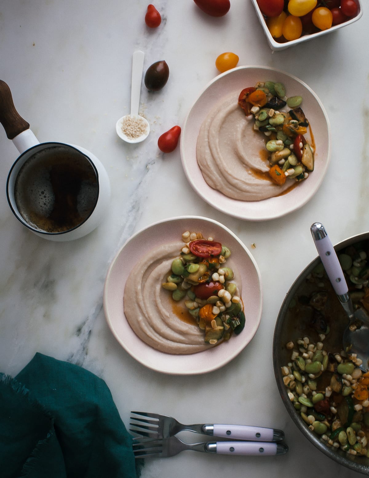 White bean puree topped with cooked vegetables and beans in two bowls with a pot nearby.