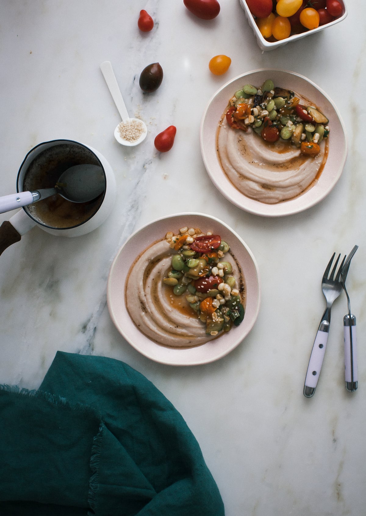 Summer succotash served with white bean puree in two bowls with forks nearby.