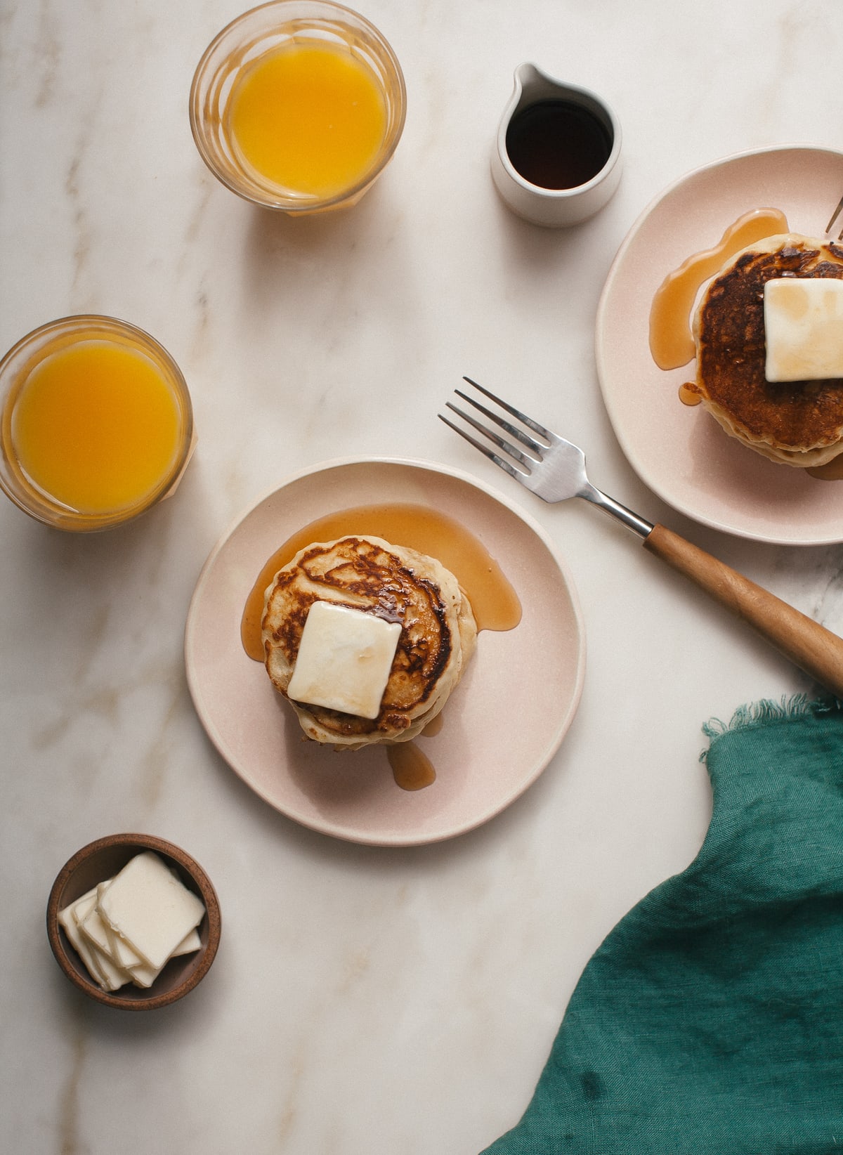 Overhead image of lemon ricotta pancakes on plates with butter and maple syrup.
