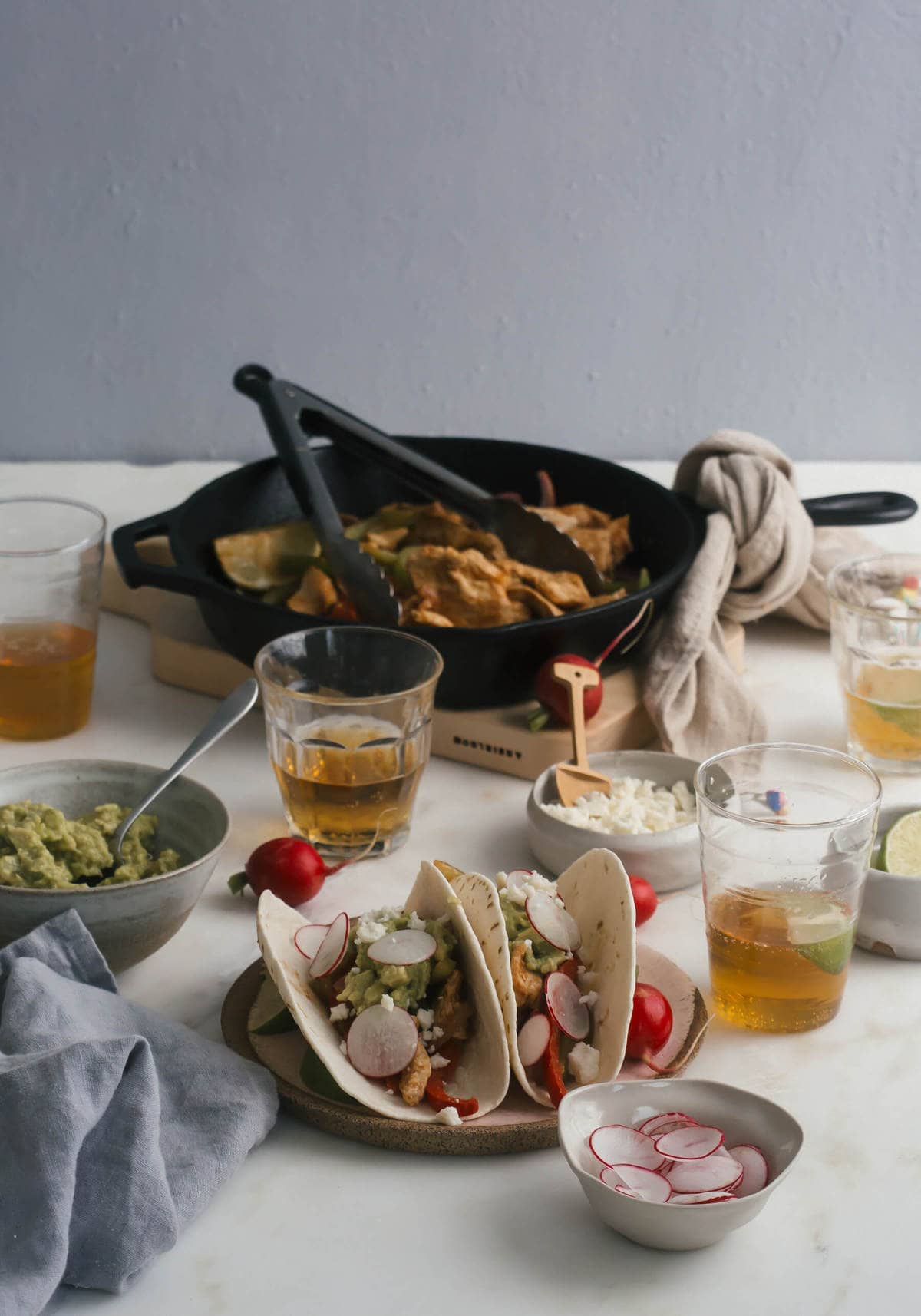 Side view of chicken fajitas on a plate with glasses of beer near by.